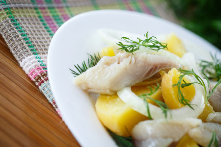 salted herring with boiled potatoes and dill on a plate