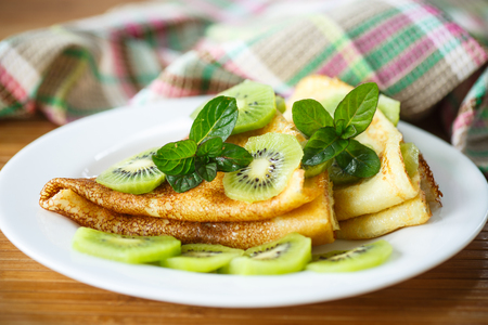 sweet tasty pancakes with kiwi on a plate with mintの写真素材