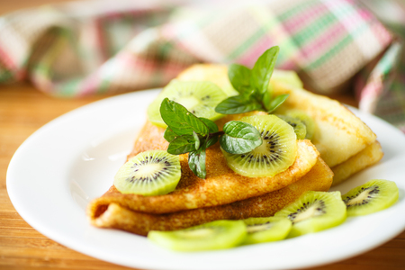 sweet tasty pancakes with kiwi on a plate with mintの写真素材