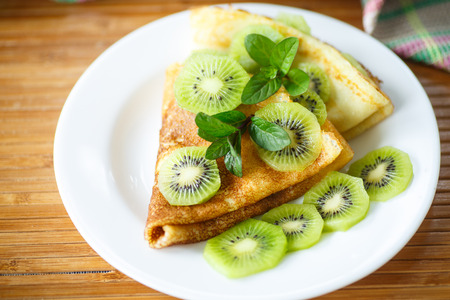 sweet tasty pancakes with kiwi on a plate with mintの写真素材