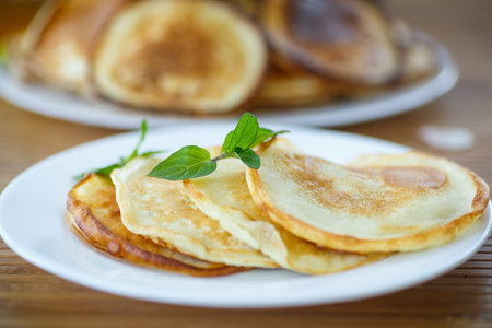 sweet tasty pancakes on a plate with a sprig of mint