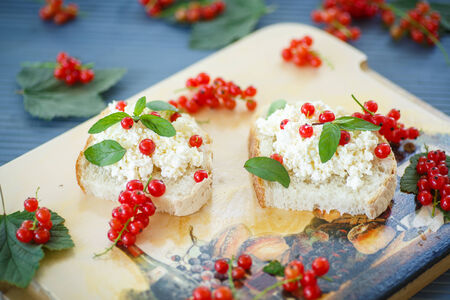 sandwich with cheese and red currants on a wooden tableの写真素材