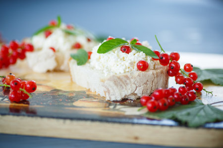 sandwich with cheese and red currants on a wooden table