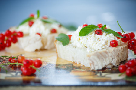 sandwich with cheese and red currants on a wooden table
