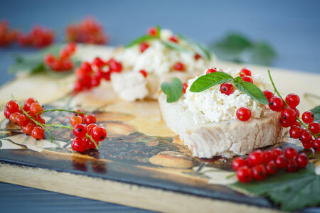 sandwich with cheese and red currants on a wooden tableの写真素材
