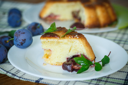 sweet cake with plums on a plate decorated with mintの写真素材