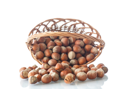 hazelnuts in a wicker basket on a white backgroundの写真素材