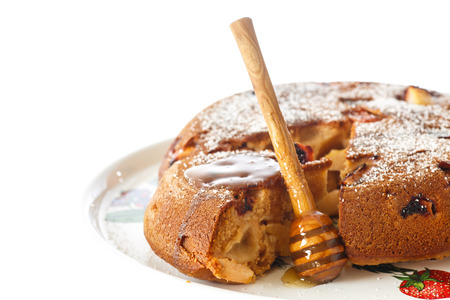 Honey cake with a wooden honey spoon on a white backgroundの写真素材