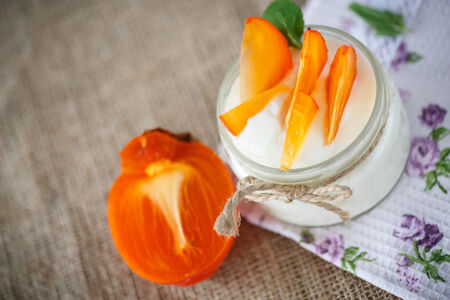 sweet homemade yogurt with persimmons in a glass jarの写真素材