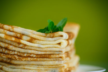 many thin pancakes on a plate on a green background