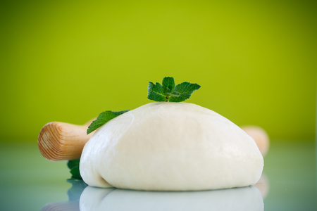 yeast dough with a wooden rolling pin on a green backgroundの写真素材