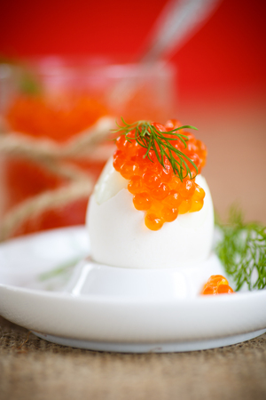 boiled egg with red caviar in a plate on the tableの写真素材