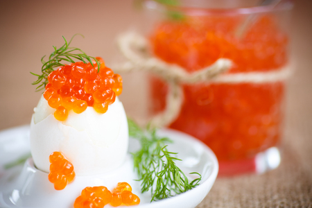 boiled egg with red caviar in a plate on the tableの写真素材