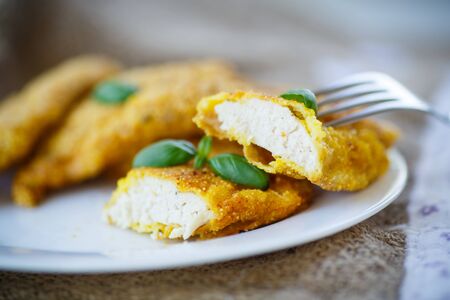 chicken fried in batter with basil on a plateの写真素材