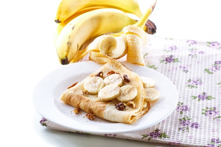 sweet pancakes with bananas and nuts on a plateの写真素材