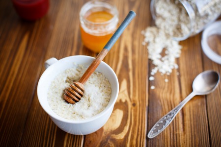 Oat milk porridge and honey in a cup on the tableの写真素材