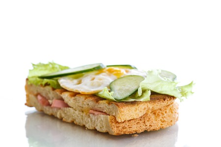 sandwich with sausage, cheese, lettuce and eggs on a white backgroundの写真素材