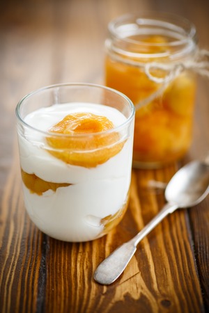 Greek yogurt with canned apricots in a glass on a wooden tableの写真素材
