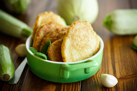 fried zucchini fritters with dill on a plateの写真素材