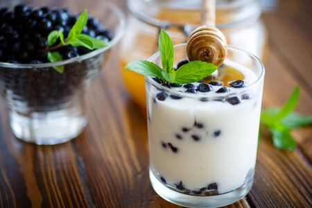 sweet homemade yogurt with blueberries and honey in a glassの写真素材