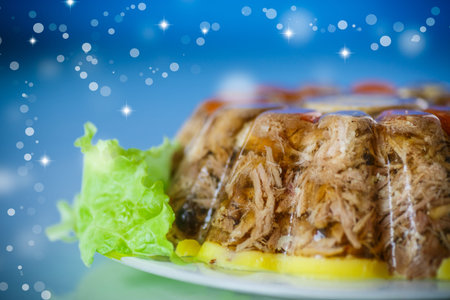 jellied meat with vegetables on blue blurred background