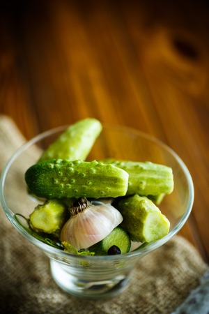 Pickled cucumbers in a glass bowl on a wooden tableの写真素材