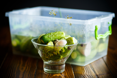 Pickled cucumbers in a glass bowl on a wooden tableの写真素材