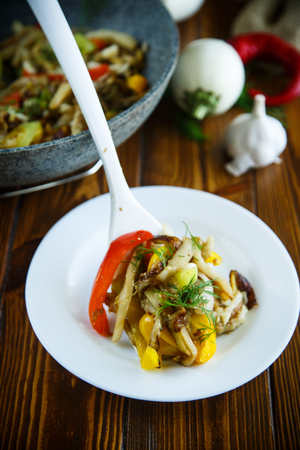 eggplant with vegetables fried in a wok, on a wooden tableの写真素材