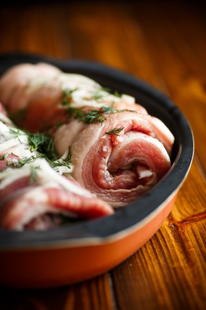 Roll of meat with various spices and herbs on a wooden tableの写真素材
