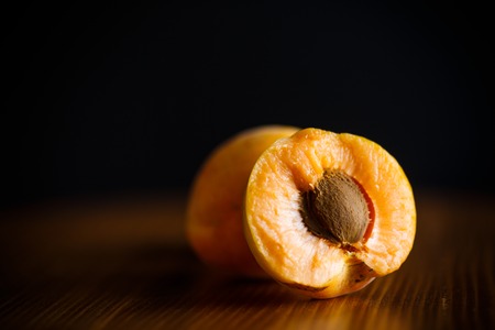 ripe two apricots isolated on a black backgroundの写真素材