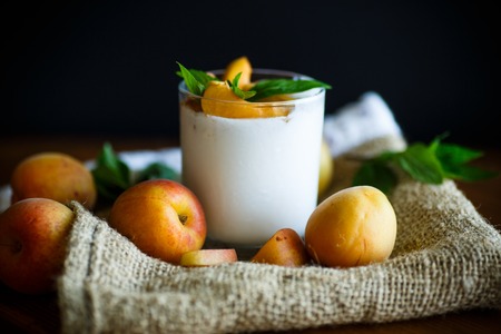 homemade yogurt with ripe apricots on wooden backgroundの写真素材