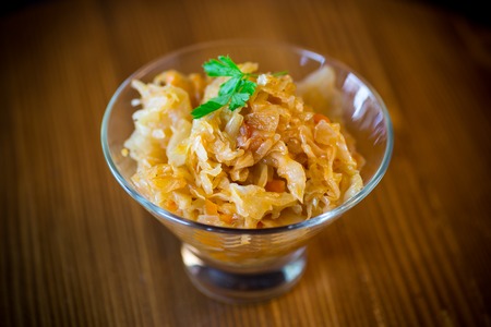 stewed cabbage with carrots in a glass bowl on a wooden tableの写真素材
