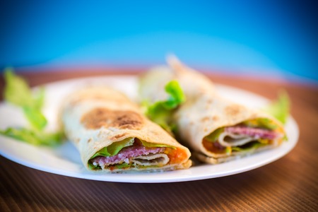 thin pancakes with salad leaves and bacon in a plate on a blue backgroundの写真素材