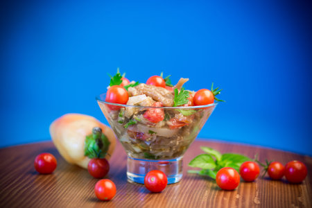 A warm salad of baked eggplant and peppers with cherry tomatoes in a glass bowlの写真素材