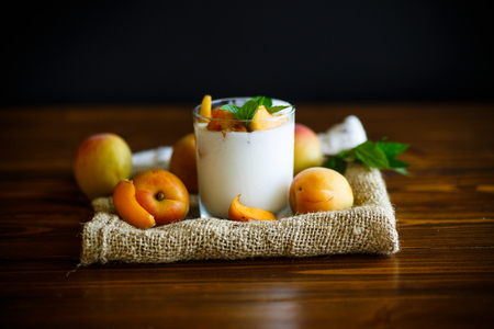 homemade yogurt with ripe apricots on wooden backgroundの写真素材
