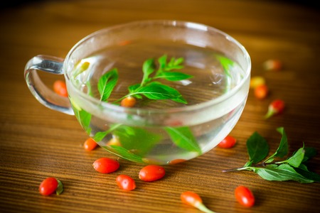hot tea from ripe red goji berries in a glass teapot on a wooden tableの写真素材