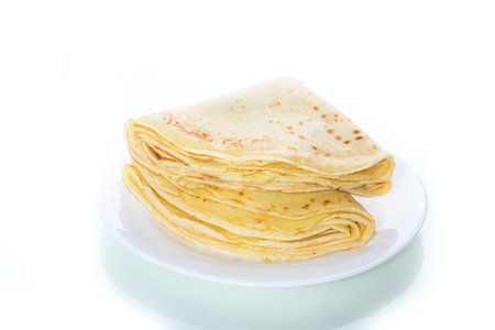 many thin fried pancakes in a plate on a white background