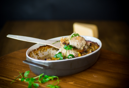 Cauliflower baked with meatballs in cheese sauce, in ceramic form on a wooden table.の写真素材