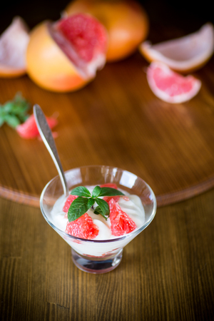 sweet homemade organic yogurt with slices of red grapefruit in a glass bowlの写真素材