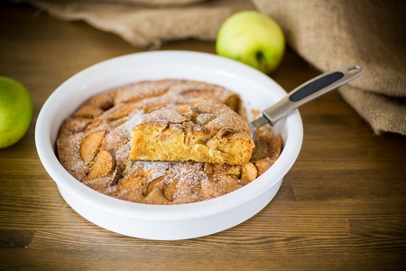 sweet apple pie in ceramic form on a woodenの写真素材