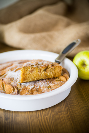 sweet apple pie in ceramic form on a woodenの写真素材