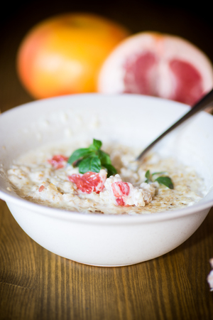 sweet oatmeal with slices of red grapefruit in a ceramic bowlの写真素材