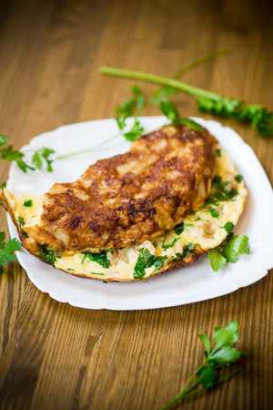 fried omelet with cauliflower and greens in a plate on a wooden tableの写真素材