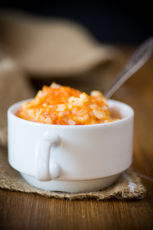 Sweet boiled pumpkin porridge with rice in a plate on a woodenの写真素材