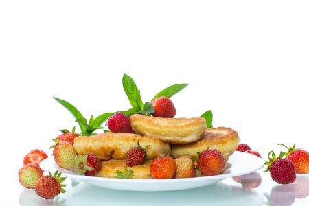 fried sweet pancakes with ripe strawberries in a plate isolated on white backgroundの写真素材