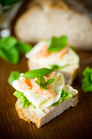 sandwich with cheese, salad leaves and red fish on a woodenの写真素材