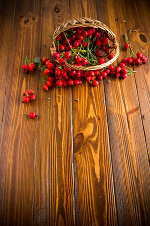 ripe red dogrose in a basket on a wooden tableの写真素材