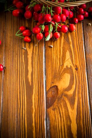 ripe red dogrose in a basket on a wooden tableの写真素材