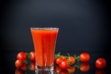 homemade tomato juice in a glass and fresh tomatoes, isolated on black backgroundの写真素材