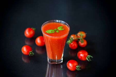 homemade tomato juice in a glass and fresh tomatoes, isolated on black backgroundの写真素材